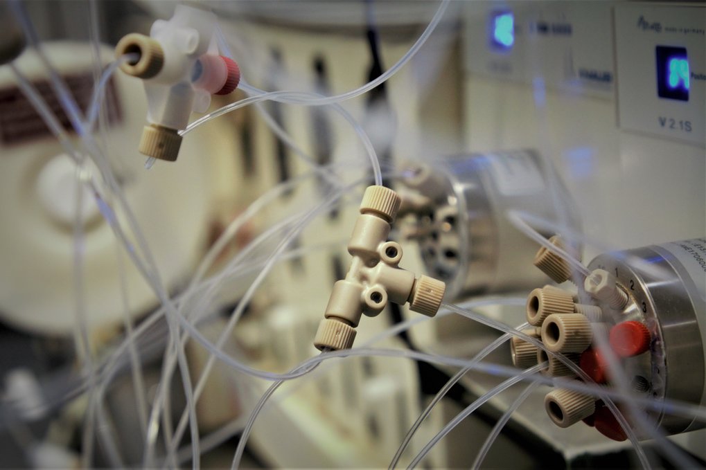 A tee mixer connected with some 1/16" tubing, in the background some multiposition valves, blurred.